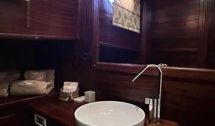Master cabin with round white bed, wood-paneled walls, and bedside lamp