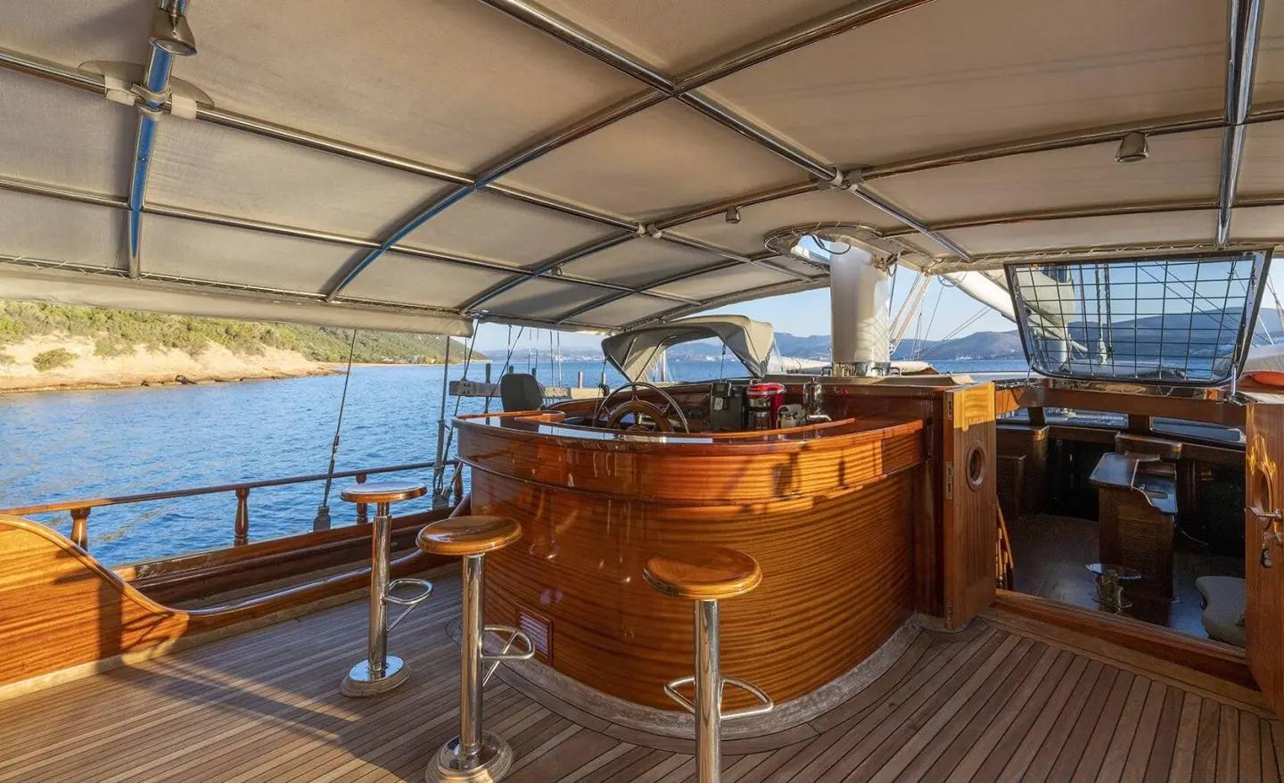 Wooden deck bar with stools under an awning, sea view on a gulet