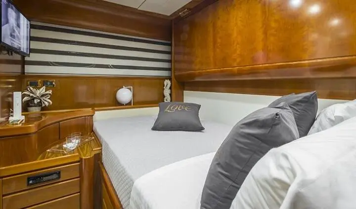 Cabin with a full bed, white linens, gray pillows, wooden cabinetry, compact lighting