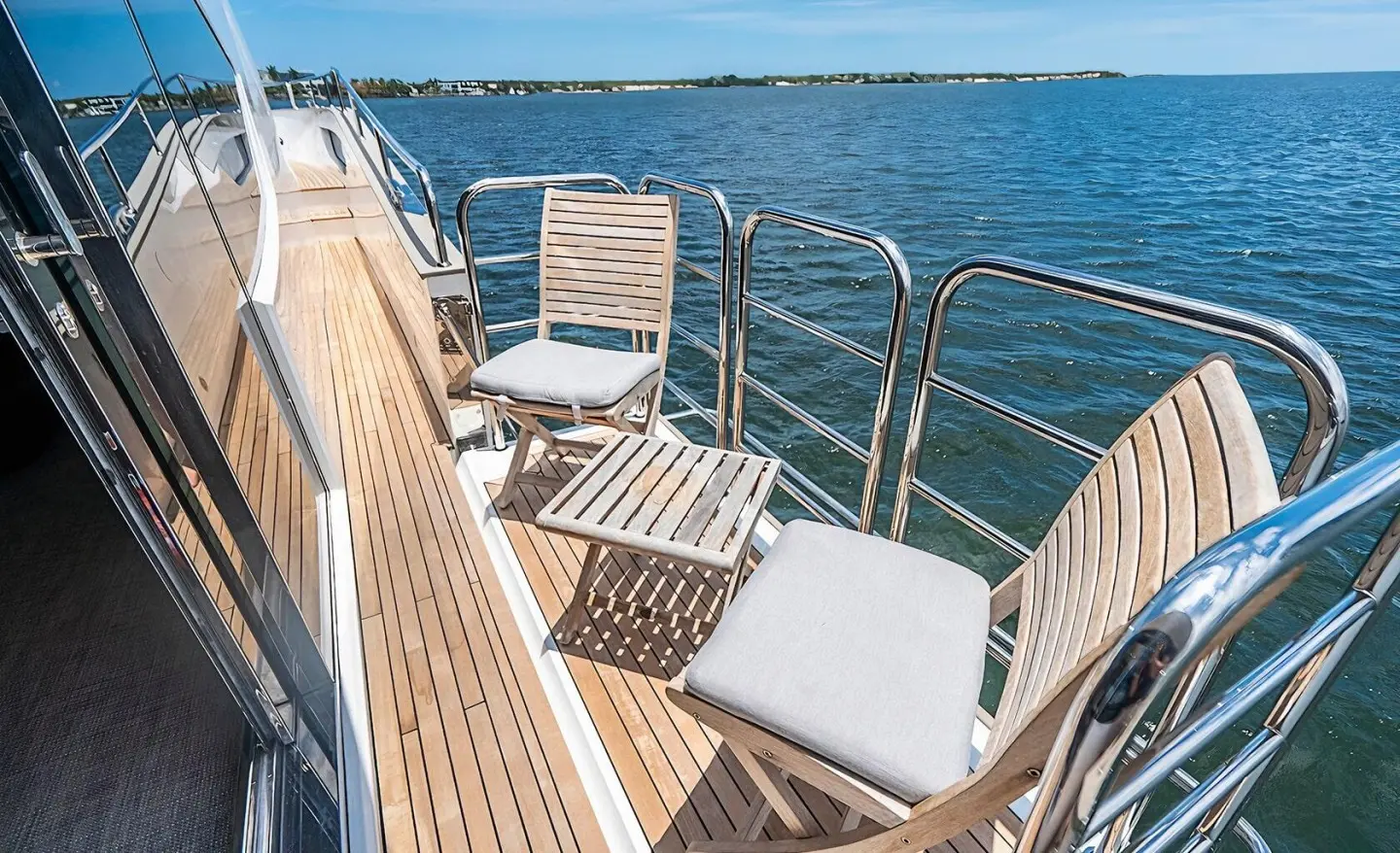 Deck seating on Quantum yacht with white chairs and railing by water
