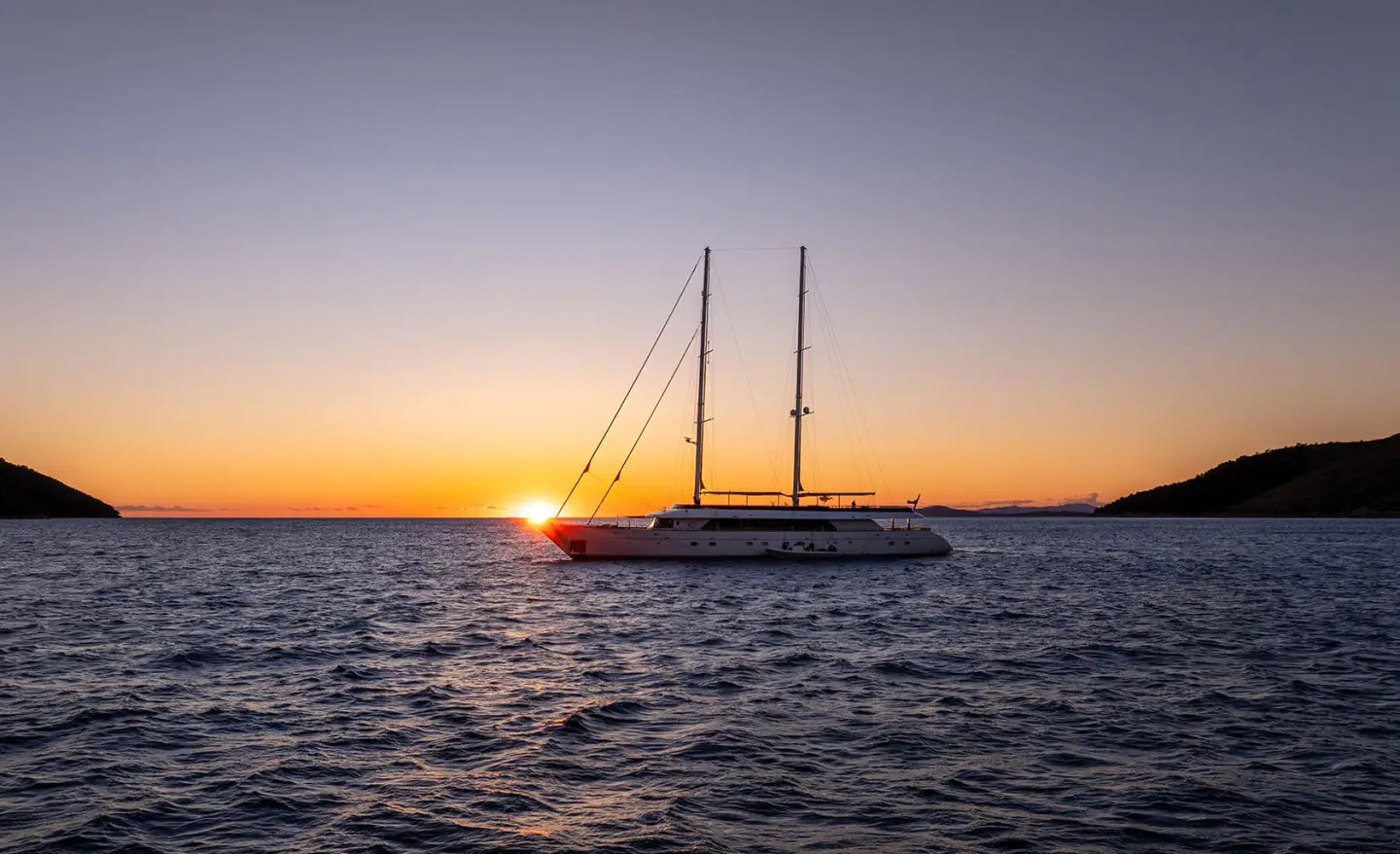 Anima Maris yacht sailing at sunset, silhouette against calm sea
