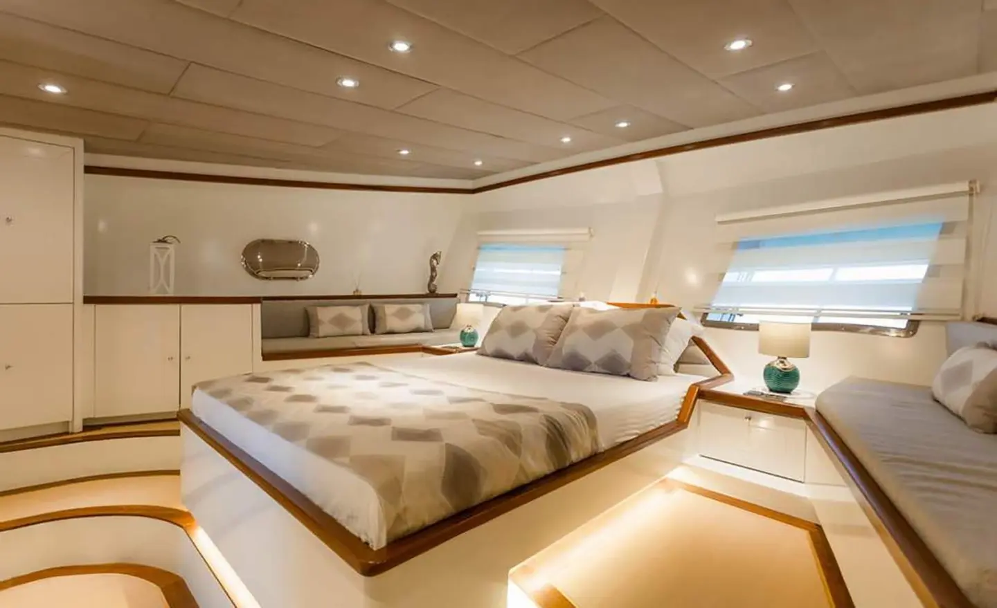A bedroom with a large bed, side windows, and built-in cabinets