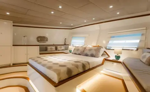 A bedroom with a large bed, side windows, and built-in cabinets