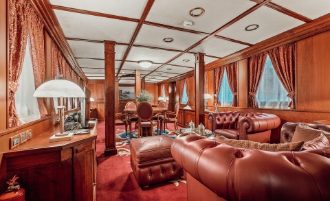 Luxury Seagull II interior: polished wood panels, burgundy leather seating, and elegant draped curtains in a spacious lounge