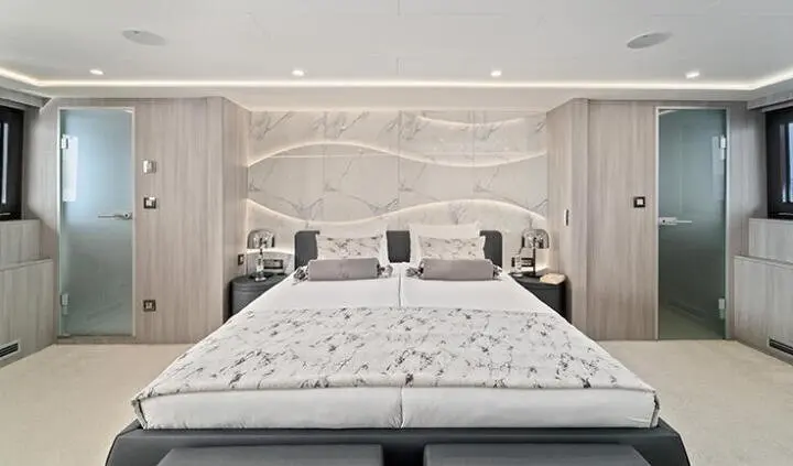 Master cabin with king bed, white bedding, and tufted headboard on a yacht