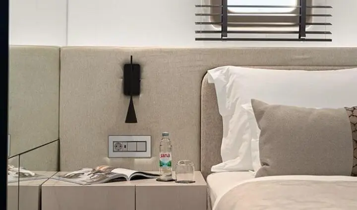 Master cabin with king bed, beige headboard, bedside lamps, and window shade