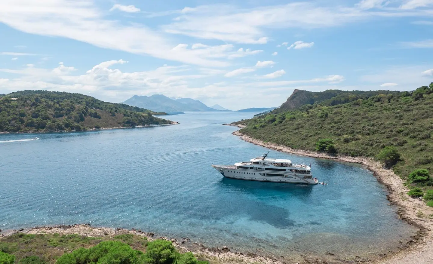 Luxurious Riva yacht anchored near rocky coastline with clear blue water