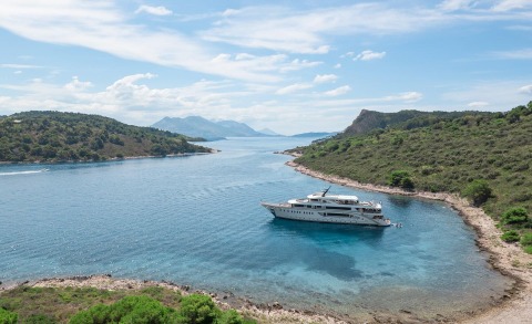 Riva luxury yacht anchored in a turquoise cove with secluded rocky shoreline