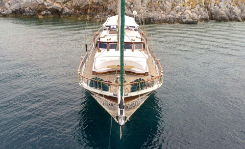 Ecce Navigo yacht viewed from bow with wooden deck and seating areas on calm water