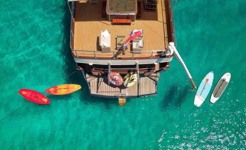 Overhead shot of a luxury yacht with deck furniture, turquoise water surrounding