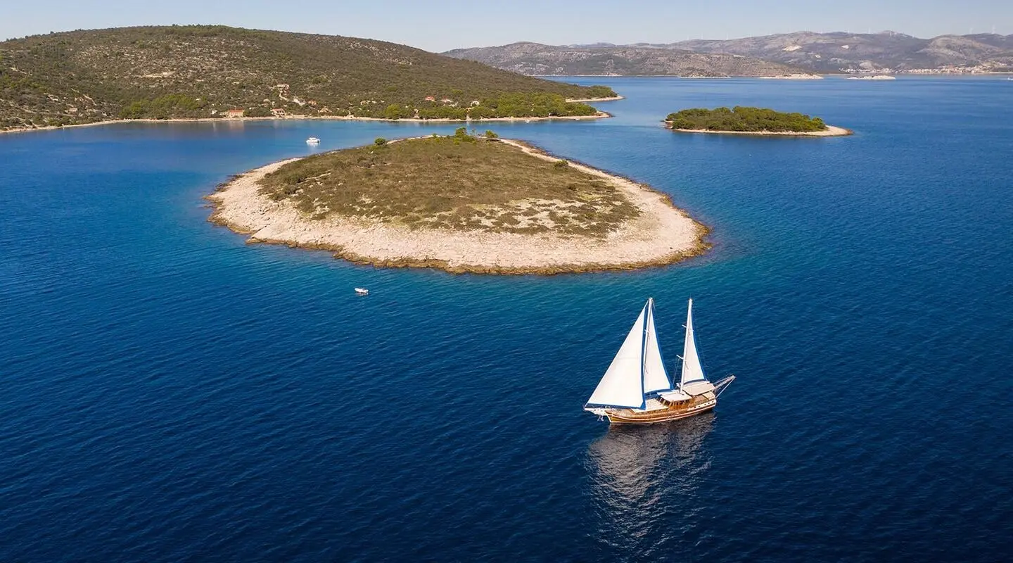 Andi Star yacht sailing near a small island at sunset with calm blue water