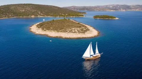 Andi Star yacht sailing near a small island at sunset with calm blue water