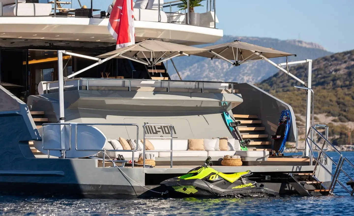 Illusion II yacht, rear deck with seating, shaded umbrella, watercraft nearby