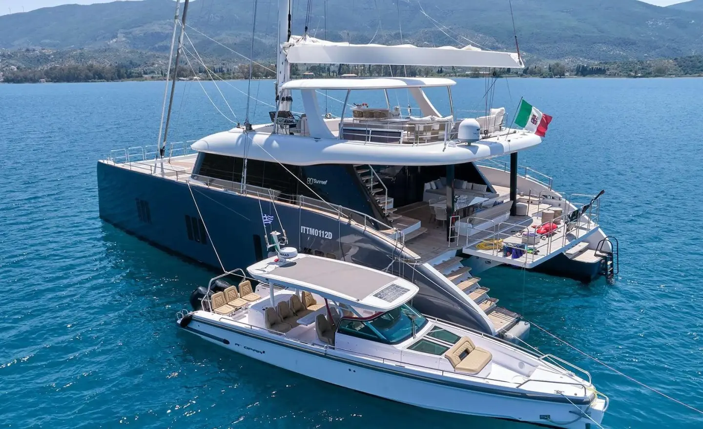 Genny luxury gulet yacht at sea with a smaller motorboat nearby at sunset