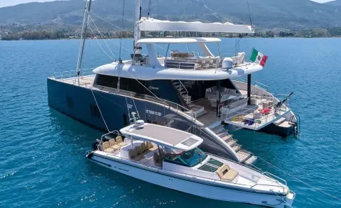 Genny luxury gulet yacht at sea with a smaller motorboat nearby at sunset