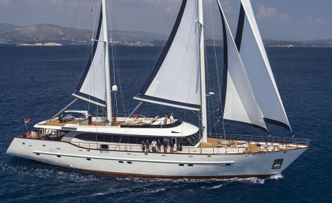 Navilux yacht on clear seas with large sails deployed, upper deck and side deck with passengers aboard