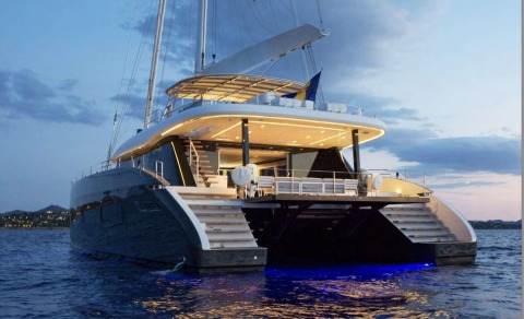 Yacht rear view with upper deck, stairs and ocean, illuminated by evening lights