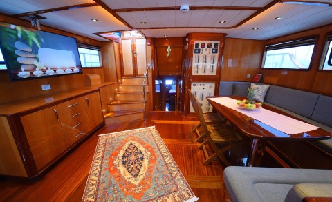 Maya luxury 26m yacht interior with wood paneling, dining table, and lounge seating