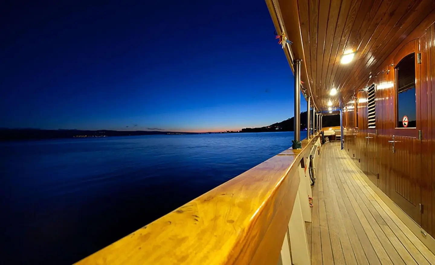 Night-lit yacht deck with wooden exterior along the railing
