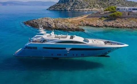 Yacht Sea Wolf anchored in clear blue water near rocky coastline