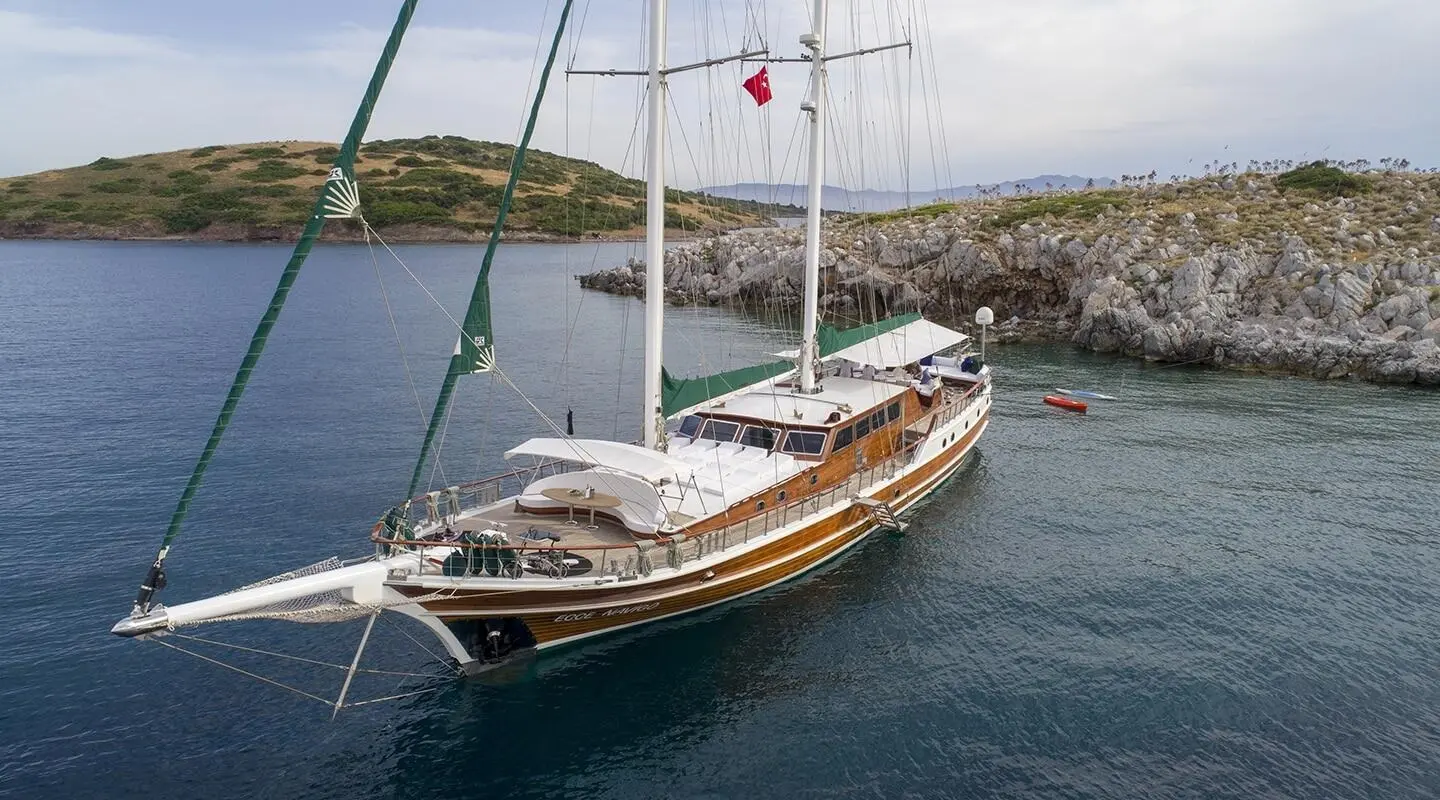 Ecce Navigo luxury gulet anchored near rocky coastline at sunset