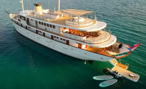 Yacht Bellezza anchored in turquoise water with people on deck