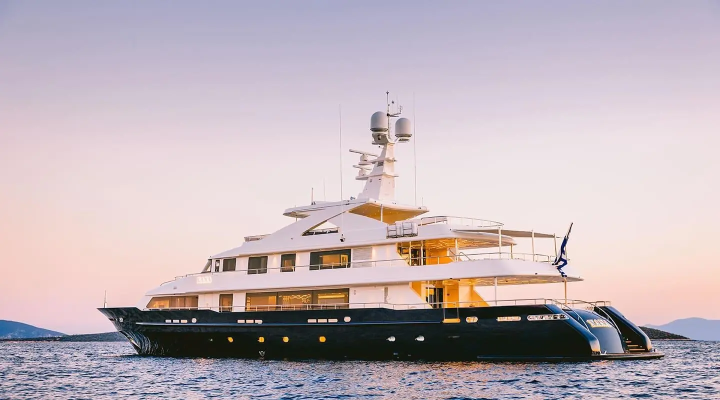 Xana yacht anchored at sea with white hull, multiple decks, orange-brown sunlit structures