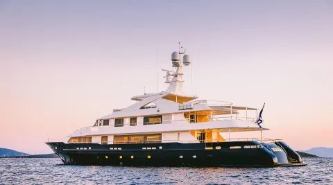 Xana yacht anchored at sea with white hull, multiple decks, orange-brown sunlit structures
