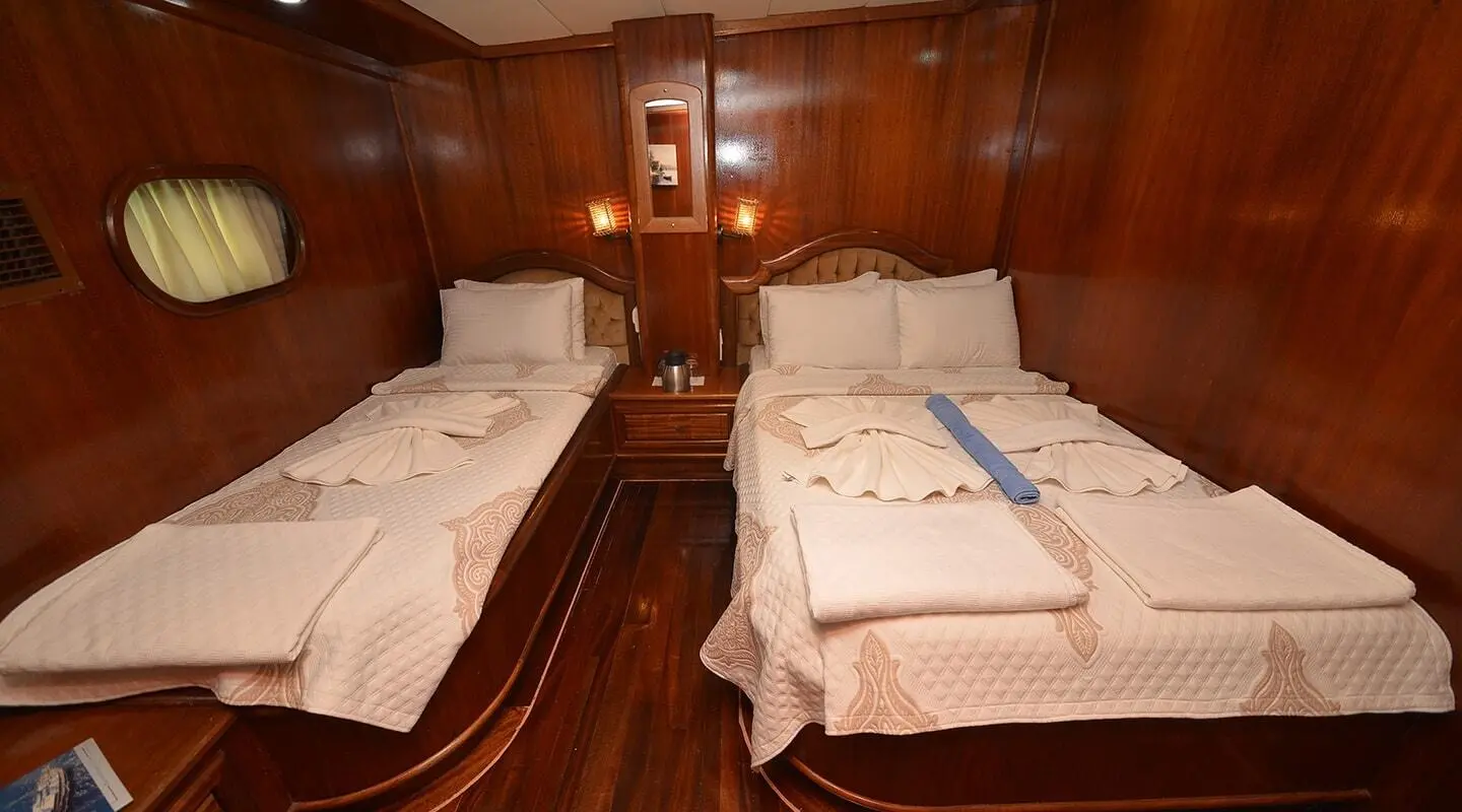 Interior of Prenses Bugce yacht with twin berths, polished wood walls, and plush bedding