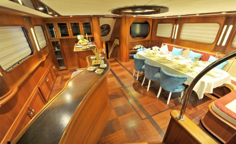 Luxurious yacht interior with wooden furniture, dining table and chairs visible