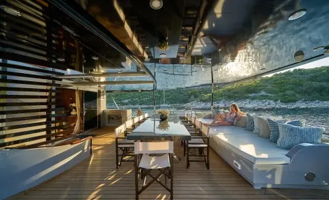 Rara Avis yacht dining on deck at sunset, table set under awning