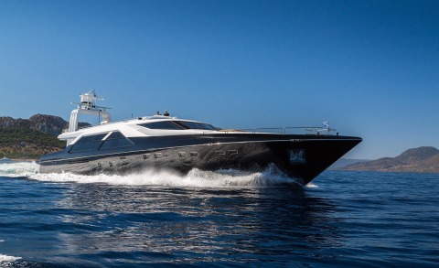 Luxurious black and white motor yacht speeding on water with bow forward and side windows visible