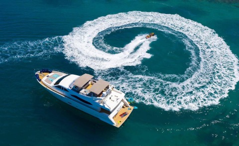 White yacht turning with foamy wake in turquoise water