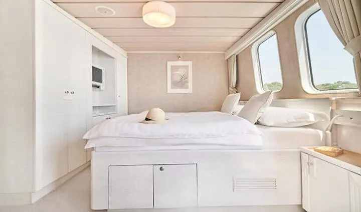 La Perla yacht cabin interior with plush bed, built-in wardrobes, and sea-view windows