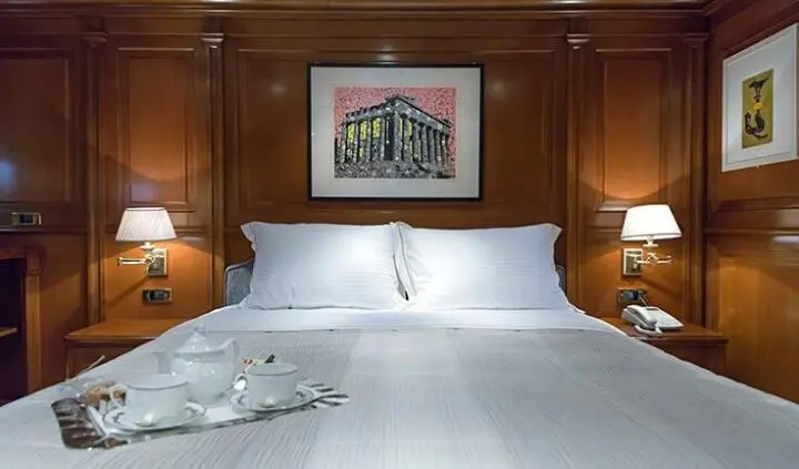 Aquila yacht cabin with a large bed, white linens, wooden headboard, and nightstands