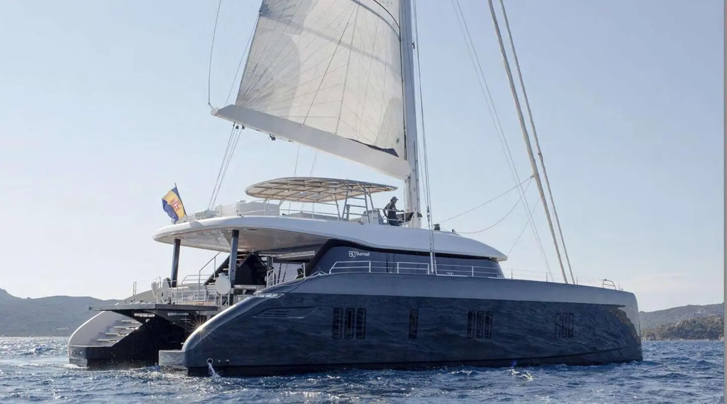 Above & Beyond yacht with sails up, seen from side on calm water at sunset