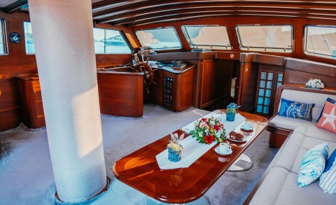 Wicked Felina yacht interior: polished wooden helm, plush seating, and a glossy table with floral centerpiece