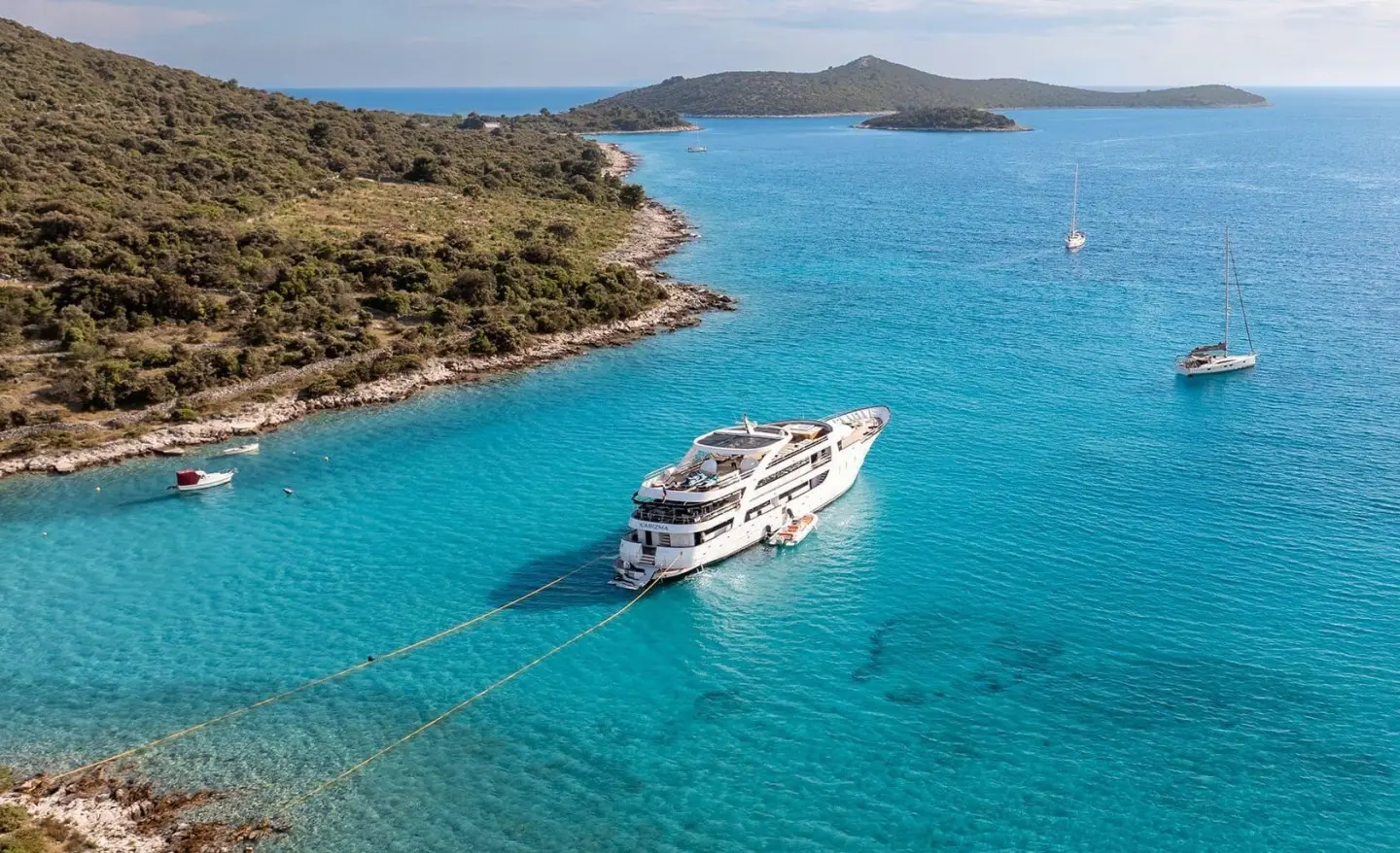 Karizma motor yacht anchored in turquoise bay near rocky coastline