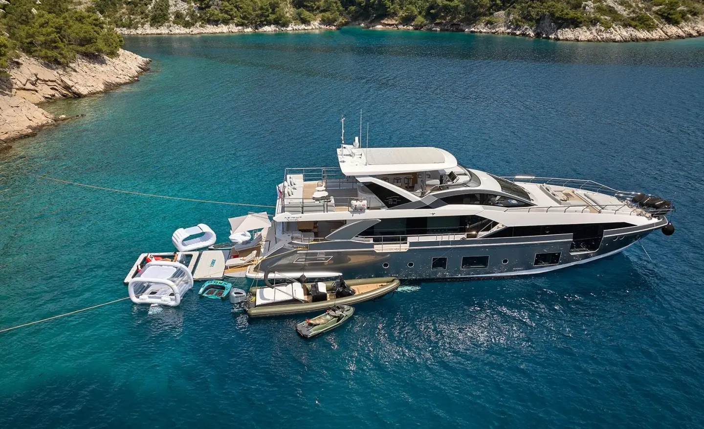 Aluminia Too yacht anchored near a coastal shoreline with small boats nearby