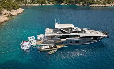 Aluminia Too yacht anchored near a coastal shoreline with small boats nearby