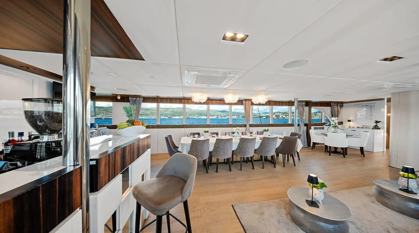 Interior of Dalmatino luxury yacht with long wooden dining table and white leather chairs