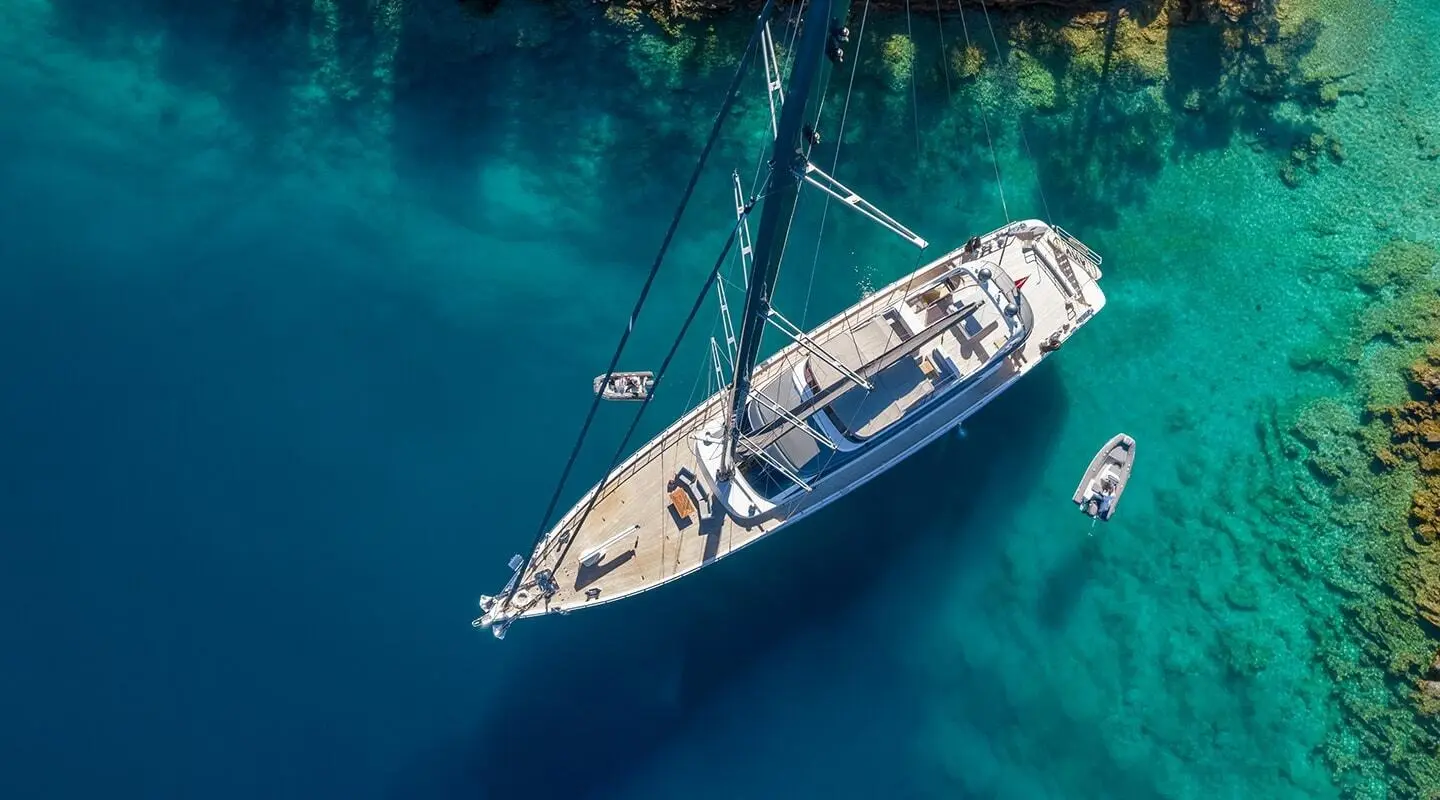 aerial view sailboat yacht in turquoise water near green shoreline