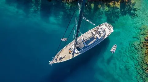 aerial view sailboat yacht in turquoise water near green shoreline