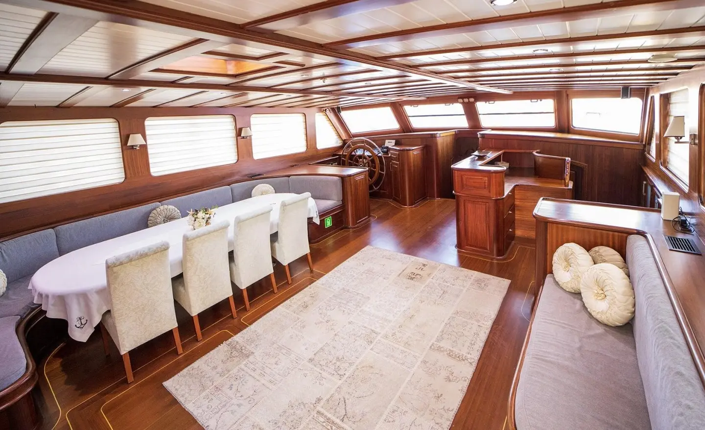 Interior of a luxurious sailing yacht with wooden tables, chairs, and soft lighting at sunset