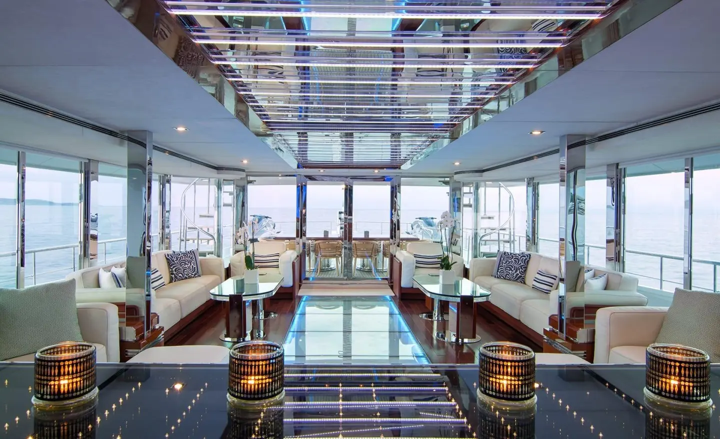 Luxurious yacht salon with glass walls, seating, and polished wood interior