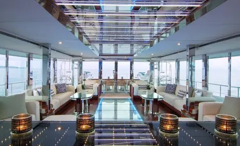 Luxurious yacht salon with glass walls, seating, and polished wood interior