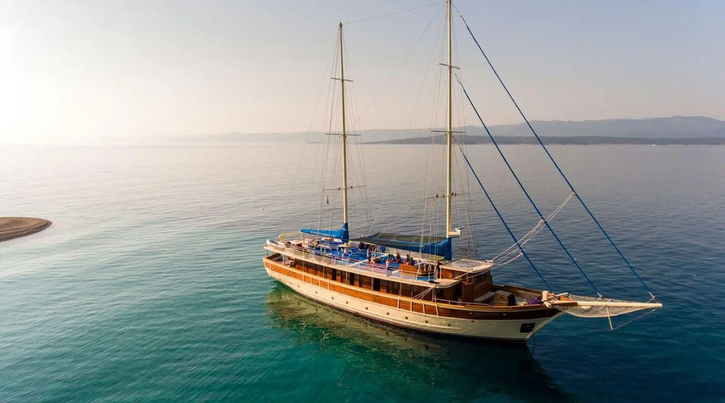 Tajna Mora luxury gulet at sunset with two masts and teal sea