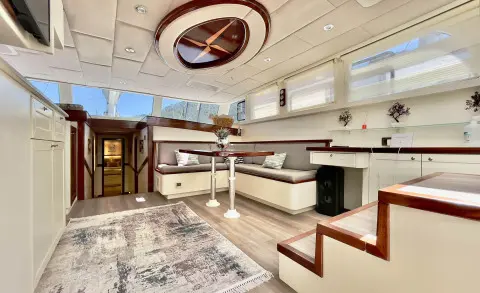 Interior of a luxury yacht with a polished white bar, seating, and ceiling skylight
