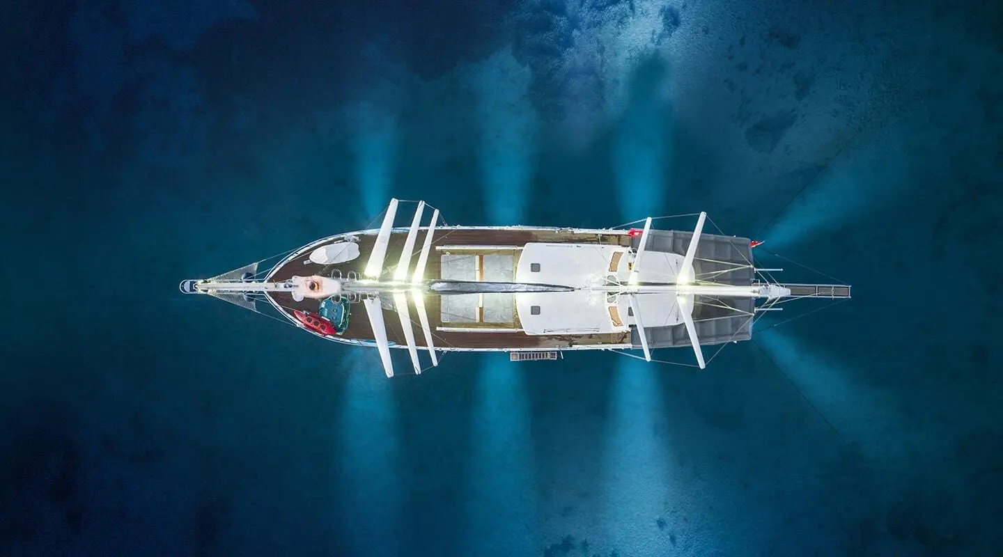 Overhead view of Lucky You yacht at sea with deck lights on and calm blue water
