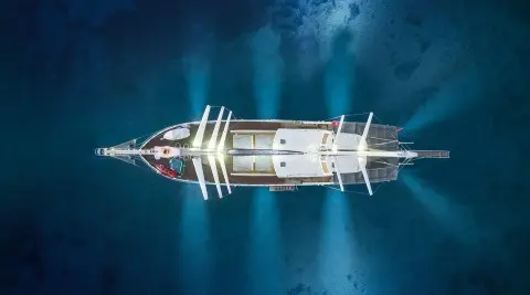 Overhead view of Lucky You yacht at sea with deck lights on and calm blue water